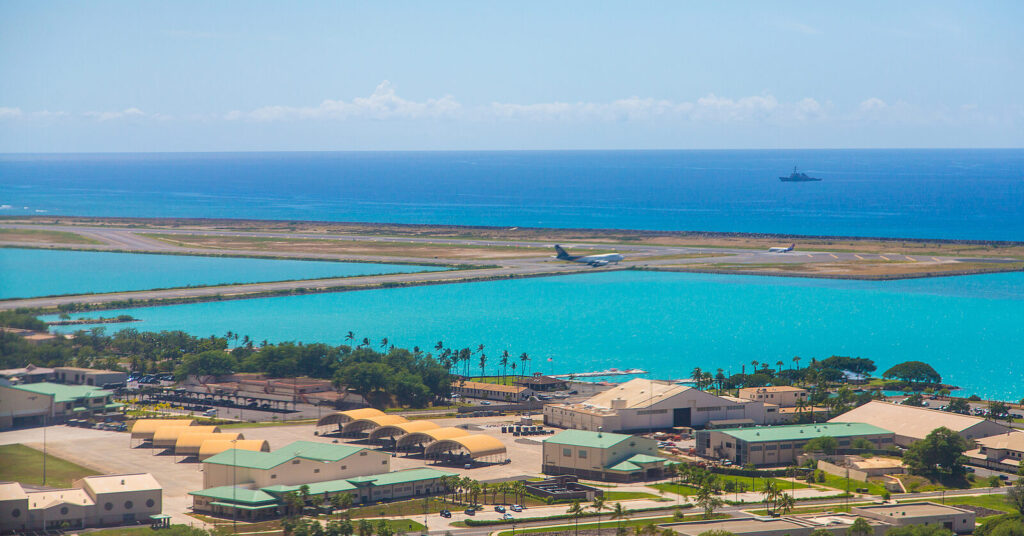 Aerial view of Lihue Airport showing the runway between the Pacific Ocean and Kauai mountains