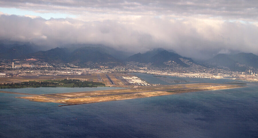 Aerial view of Lihue Airport showing the runway between the Pacific Ocean and Kauai mountains