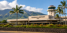 Kahului Airport terminal and control tower with tropical palms and Maui mountains