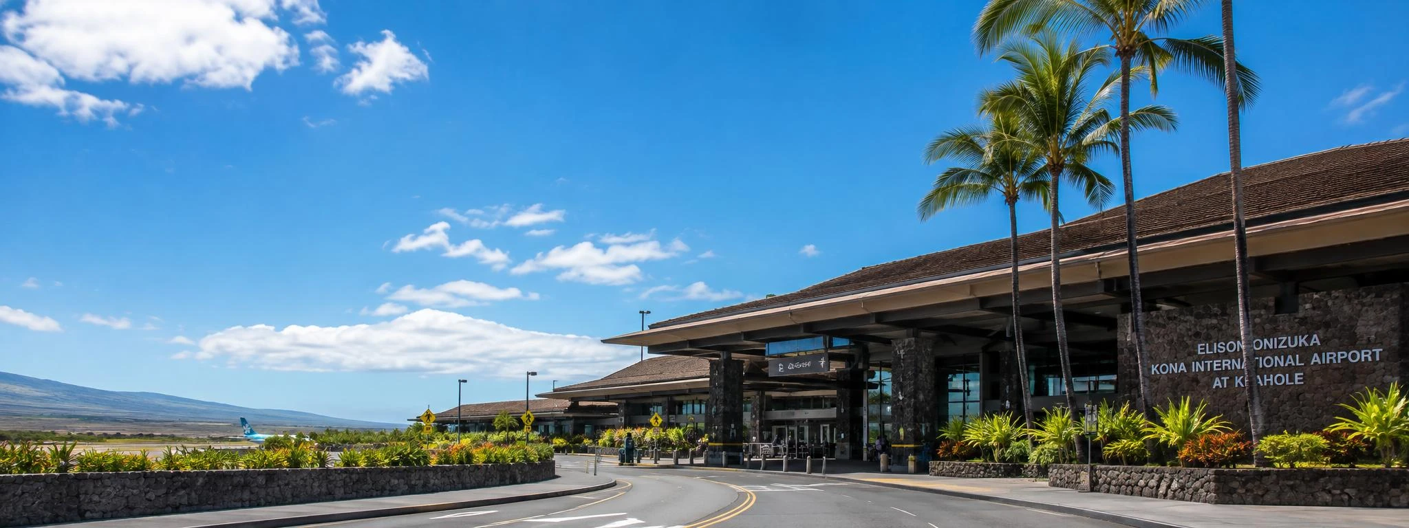 Kona International Airport terminal on Hawaii Island with palm trees and volcanic landscape